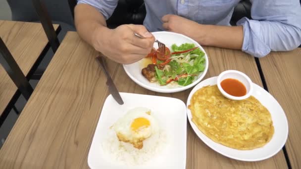 Thai cuisine - rice, omelet, vegetables with pork. a man eats Thai food in a restaurant. 4k, slow motion — Stock Video