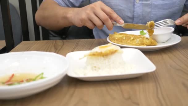 Cozinha tailandesa - arroz, omelete, verduras com o porco. Um homem come comida tailandesa num restaurante. 4k, câmera lenta — Vídeo de Stock