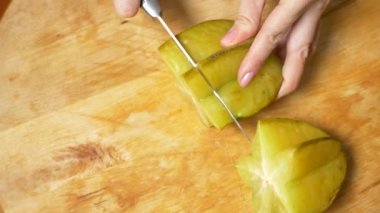 egzotik meyveler masanın üzerinde. 4k, eller bir carambola bir kesme tahtası, ağır çekim bir bıçak ile kesmek