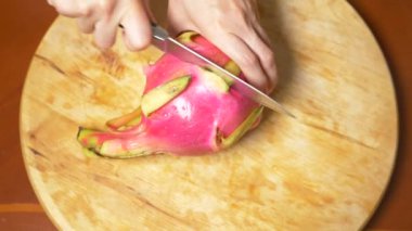 egzotik meyveler masanın üzerinde. 4k, parçalar halinde kesilmesi bir kesme tahtası üzerinde bir bıçakla bir dragonfruit eller