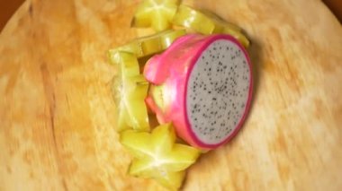 egzotik meyveler masanın üzerinde. 4k, carambola ve Dragonfruit, parçalar halinde kesilmiş bir kesme tahtası üzerinde döner.