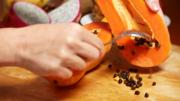 Fruits exotiques sur la table. 4k, les mains des femmes préparent la papaye pour une planche à découper — Video