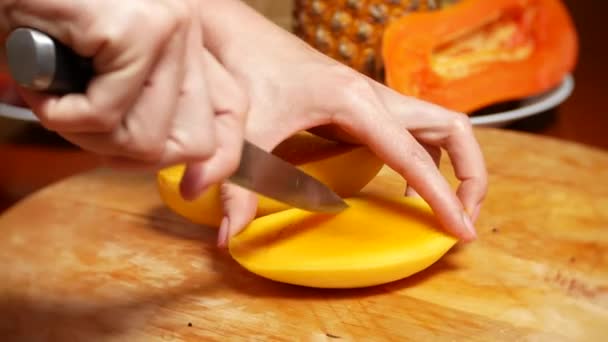 Egzotikus gyümölcs az asztalon. 4k, női kezek előkészítése mangó a daraboló-board, — Stock videók