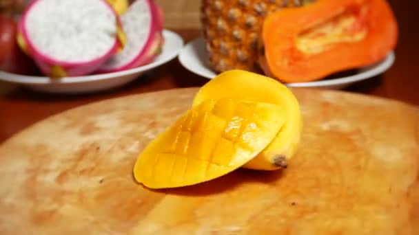 Egzotikus gyümölcs az asztalon. 4 k, mangó, passiógyümölcs, gyümölcs, darabokra vágva, forog a daraboló-board — Stock videók