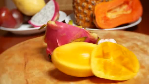 Fructe exotice pe masă. 4k, carambola și fructe de dragon, papaya, mango, mangosteen și longan, fructe de pasiune, fructe tăiate în bucăți, rotiți pe o placă de tăiere — Videoclip de stoc