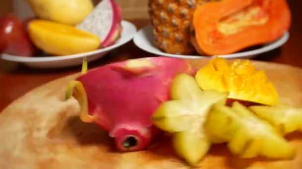 桌上有异国情调的水果。4k、杨桃、龙果、木瓜、芒果、山竹、龙眼、激情果、果切成片、旋转在切板上 — 图库视频影像