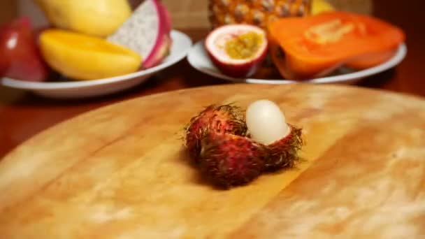 Exotische Früchte auf dem Tisch. 4k. Rambutan, rotiert auf einem Schneidebrett. — Stockvideo