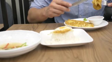 Tayland Mutfağı - pirinç, omlet, domuz eti sebzelerle. bir adam bir restoranda Tayland yemekleri yiyor. 4k, ağır çekim