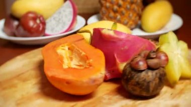 egzotik meyveler masanın üzerinde. 4 k, carambola ve dragon meyve, papaya, mango, mangosten ve longan, tutku meyve, meyve parçaları, bir kesme tahtası üzerinde döndürme kesmek