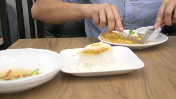 Thaise keuken - rijst, omelet, groenten met varkensvlees. een man eet Thais eten in een restaurant. 4k, slow-motion — Stockvideo