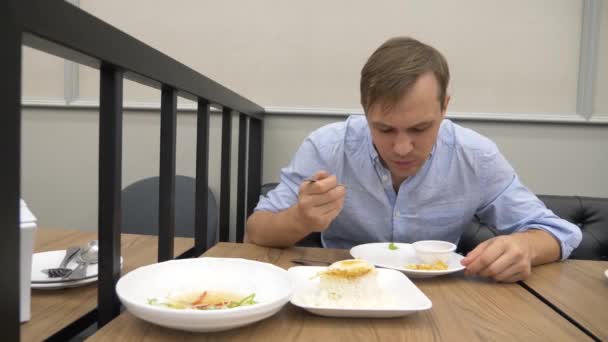 Cozinha tailandesa - arroz, omelete, verduras com o porco. Um homem come comida tailandesa num restaurante. 4k, câmera lenta — Vídeo de Stock