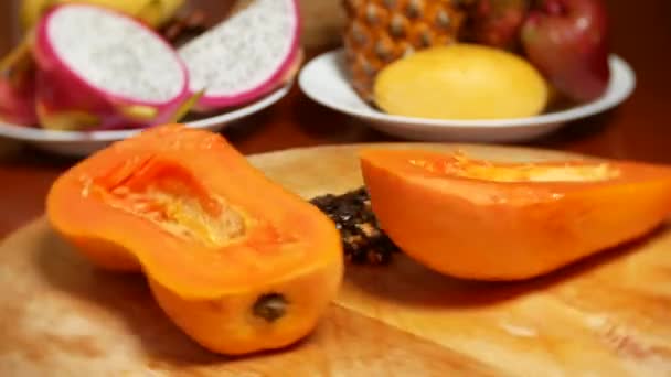 Exotiska frukter på bordet. 4k, papaya, frukt skära i bitar, rotera på en skärbräda. — Stockvideo