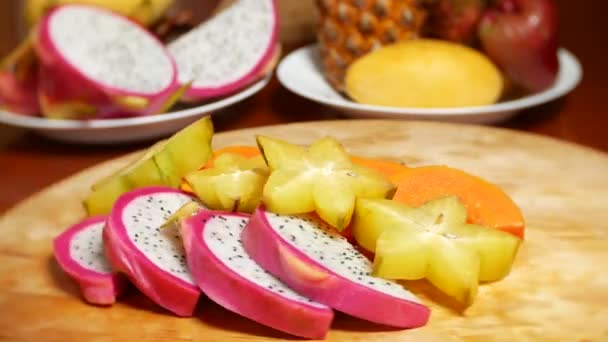 Frutas exóticas en la mesa. 4k, carambola y fruta de dragón, papaya, fruta de la pasión, fruta cortada en trozos, rotar en una tabla de cortar — Vídeos de Stock