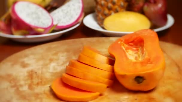Fruits exotiques sur la table. 4k, papaye, fruits coupés en morceaux, tourner sur une planche à découper . — Video