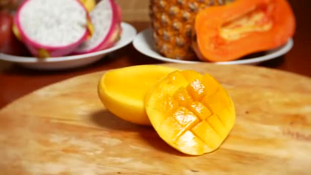 Екзотичні фрукти на столі. 4k, манго, фрукти пристрасті, фрукти нарізані шматочками, обертаються на обробній дошці — стокове відео
