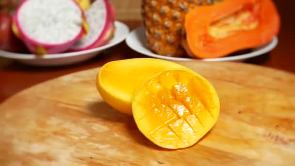 Exotiska frukter på bordet. 4 k, mango, passionsfrukt, frukt skuren i bitar, rotera på en skärbräda — Stockvideo