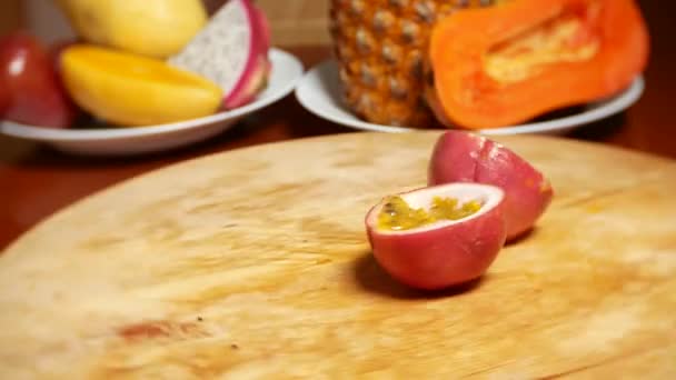 Exotiska frukter på bordet. 4 k. passionsfrukt, roterar på en skärbräda. — Stockvideo
