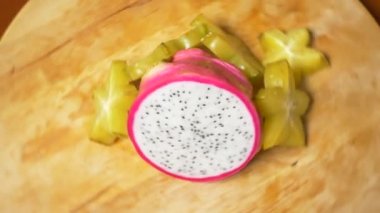 egzotik meyveler masanın üzerinde. 4k, carambola ve Dragonfruit, parçalar halinde kesilmiş bir kesme tahtası üzerinde döner.