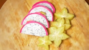egzotik meyveler masanın üzerinde. 4k, carambola ve Dragonfruit, parçalar halinde kesilmiş bir kesme tahtası üzerinde döner.