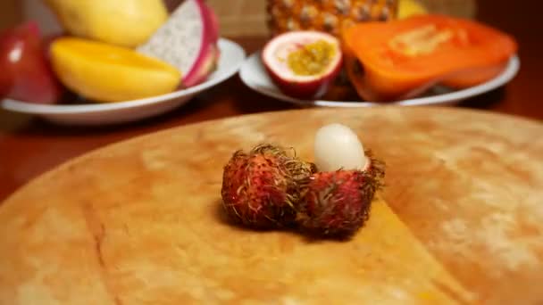 Exotic fruits on the table. 4k. rambutan, rotates on a cutting board. — Stock Video