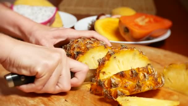 Fruits exotiques sur la table. 4k, les mains féminines coupent l'ananas avec un couteau sur une planche à découper , — Video