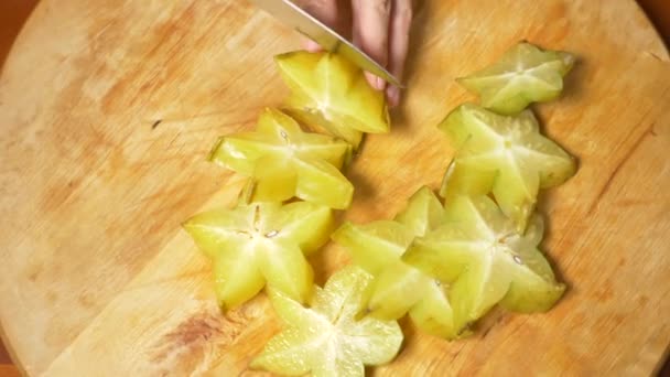 Egzotycznych owoców na stole. 4k, kobiecych rąk carambola cięcie nożem na pokładzie cięcia, Slow motion — Wideo stockowe