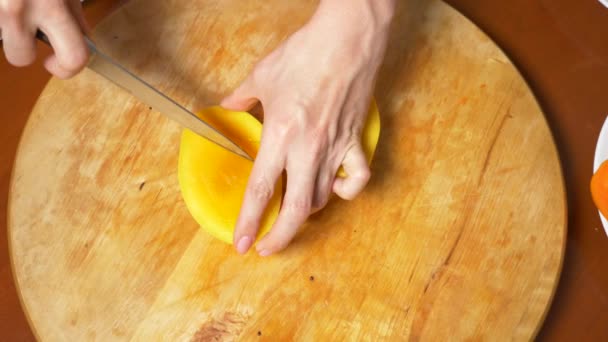 Egzotikus gyümölcs az asztalon. 4k, női kezek előkészítése mangó a daraboló-board, — Stock videók