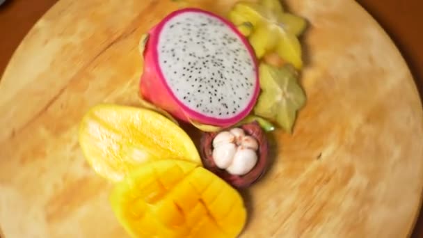 Exotische vruchten op de tafel. 4 k, carambola's en dragon fruit, papaya, mango, Mangostan en longan, passievrucht, fruit, snijd in stukjes, draaien op een snijplank — Stockvideo