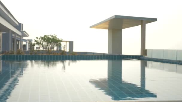 Una lussuosa piscina sul tetto della casa con vista sul mare. Al tramonto. 4k, rallentatore, bagliore solare sull'acqua. sfocatura sfondo — Video Stock