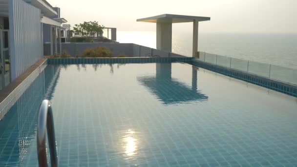 A fényűző medence a tetőn, a ház a tengerre. A naplemente. 4k, lassú mozgás, napenergia vakító fény a vízen. életlenítés háttér — Stock videók