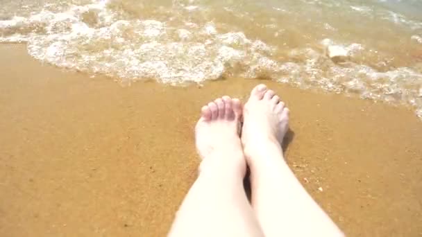 Pés femininos na areia, a onda do mar cobre as pernas femininas. 4k, câmera lenta — Vídeo de Stock