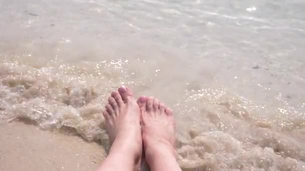 Pies femeninos en la arena, la ola marina cubre las piernas femeninas. 4k, cámara lenta — Vídeo de stock