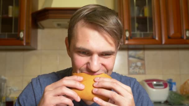 Bir adam mutfağında oturan zevkle bir elma meyveli turta yiyor. 4k, ağır çekim — Stok video
