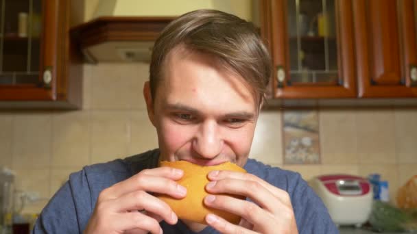 Een man eet een appel strudel met plezier, zittend in zijn keuken. 4k, slow-motion — Stockvideo