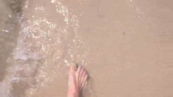 Pieds féminins sur le sable, la vague de la mer couvre les jambes féminines. 4k, au ralenti — Video