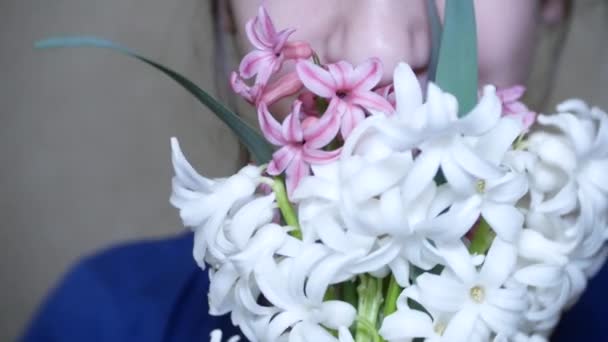 A menina cheira um buquê de jacintos brancos e rosa. 4k . — Vídeo de Stock