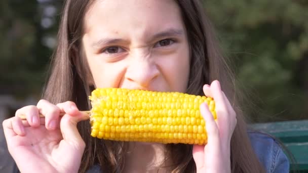 Молодая забавная девочка-подросток ест вареную кукурузу. 4k, slow-motion, крупным планом . — стоковое видео