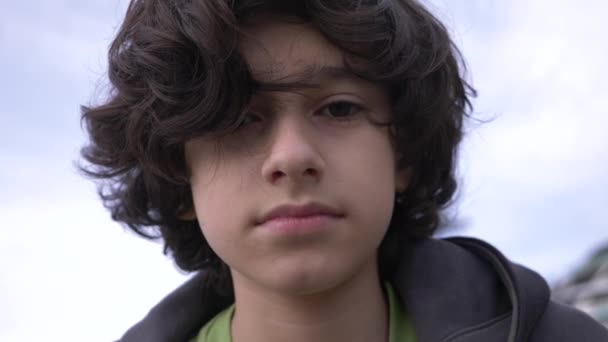 Симпатичний підліток з кучерявим волоссям проти блакитного неба 4k, повільна стрільба — стокове відео
