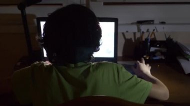 çocuk 4 k, arka görünümünden karanlık bir odada bir dizüstü bilgisayar kullanarak