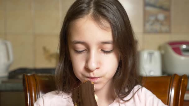 Tiener meisje eet chocolade éclair met plezier. 4k, slow-motion — Stockvideo