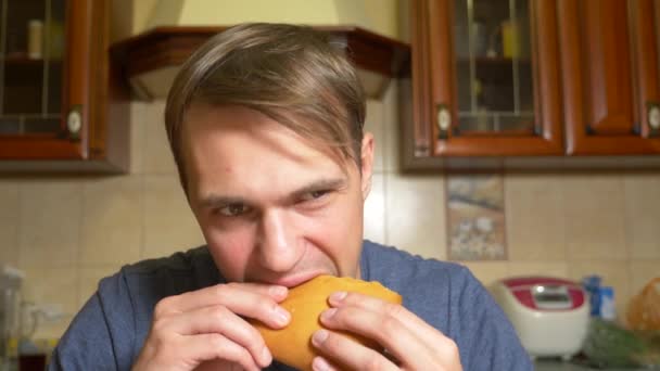Человек с удовольствием ест яблочный штрудель, сидя на кухне. 4k, slow motion — стоковое видео