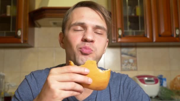 A man eats an apple strudel with pleasure, sitting in his kitchen. 4k, slow motion — Stock Video