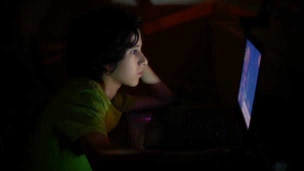 Menino usa um laptop em um quarto escuro, 4k , — Vídeo de Stock