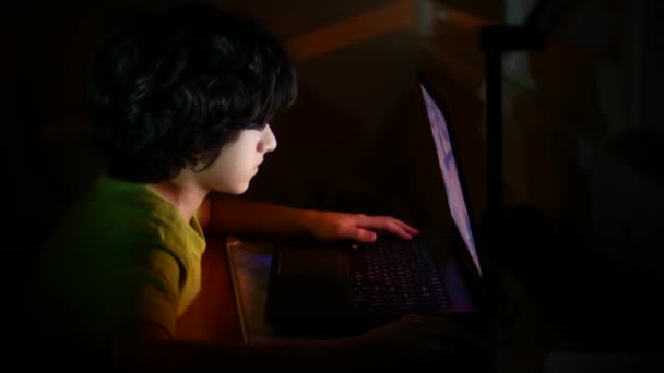 Junge benutzt einen Laptop in einem dunklen Raum, 4k, — Stockvideo
