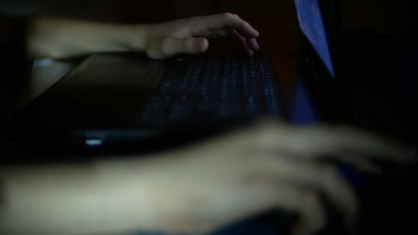 Der Junge benutzt einen Laptop in einem dunklen Raum, 4k, Nahaufnahme einer Kinderhand, die eine Computermaus und Tastatur verwendet — Stockvideo