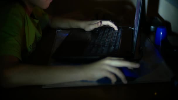 El muchacho usa el portátil en el cuarto oscuro, 4k, el primer plano de la mano infantil que usa el ratón de ordenador y el teclado — Vídeos de Stock