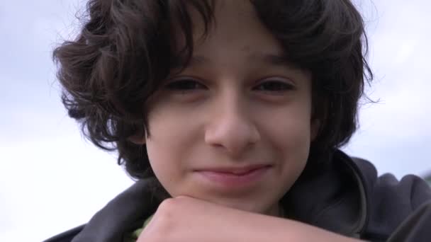 Adolescent mignon avec les cheveux bouclés contre le ciel bleu 4k, tir au ralenti — Video