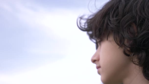 Симпатичный подросток с вьющимися волосами на фоне голубого неба 4К, замедленная съемка — стоковое видео