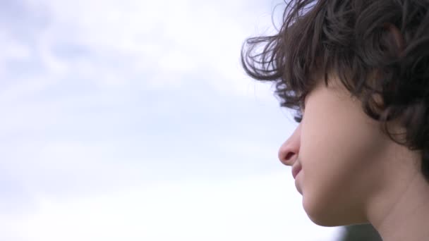 Χαριτωμένος έφηβος με σγουρά μαλλιά κατά το μπλε του ουρανού 4k, αργή κίνηση γυρίσματα — Αρχείο Βίντεο