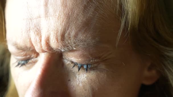 Movimento lento da vicino: lo strappo esce da un occhio e scende lungo la guancia. Donna triste con occhi azzurri dipinti che piangono — Video Stock